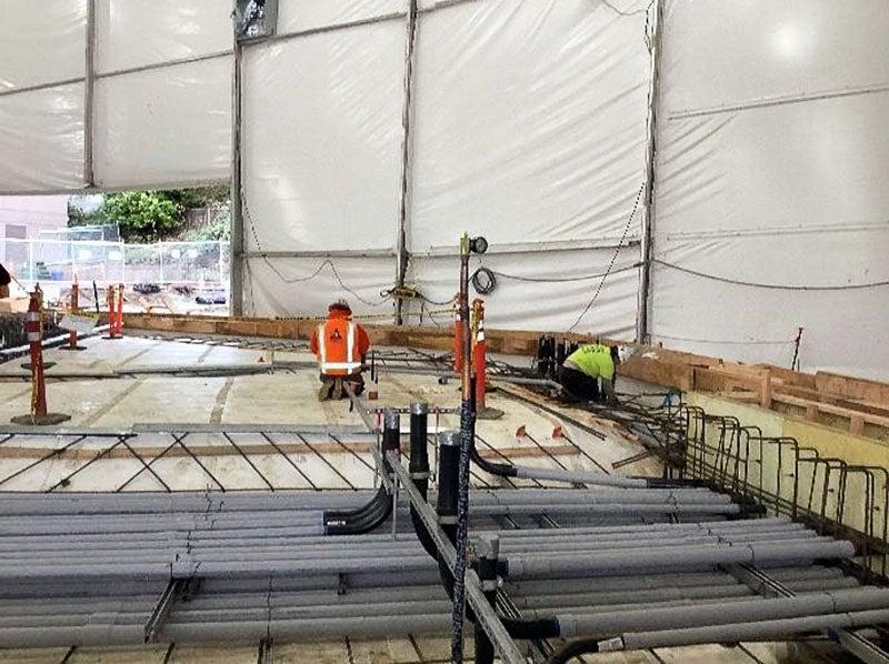 在一个大帐篷下, 白色防水材料有一堆电线导管放置在一个guie框架与钢筋下面